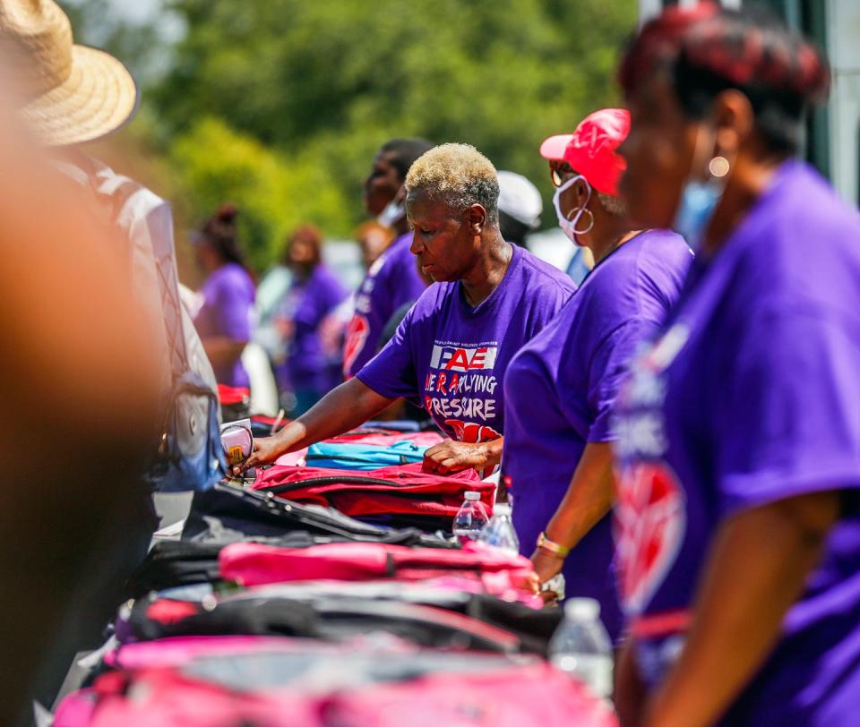 Event staffers arrange backpacks on tables during the 22nd annual Stop the Violence Back to School Rally on July 31, 2021 at Citizens Park.