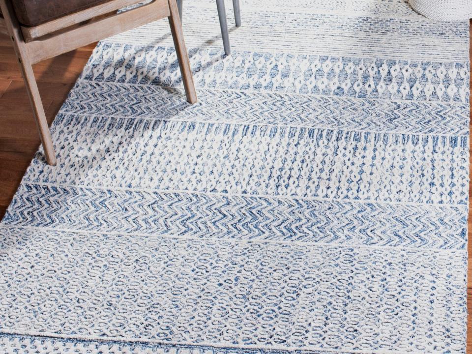 blue patterned viscose rug on a floor with furniture on top in the corner