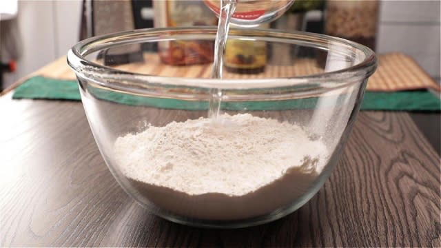 Pouring water into flour and salt in a mixing bowl