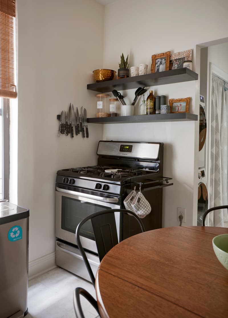 Floating shelves above oven in corner of white kitchen.