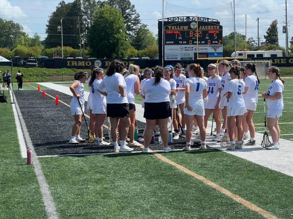 Fort Mill head coach Kirsten Terry (middle, white shirt sleeves rolled up) talks to her team during a timeout in the second quarter of the SCHSL 5A Girls Lacrosse State Championship Game on April 27.