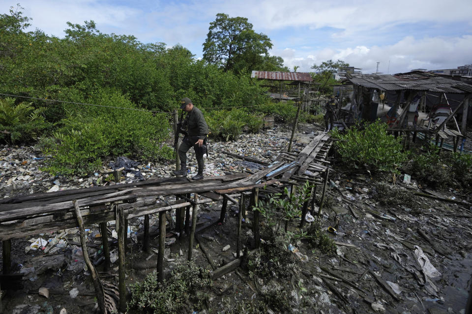 Police walk on a bridge above a mangrove-cloaked river as they patrol a neighborhood abandoned by residents due to the presence of criminal gangs in Buenaventura, Colombia, Thursday, Aug. 17, 2023. The river is one of the key channels used by gangs to move drugs and weapons through this long-neglected swath of Colombia’s Pacific coast. (AP Photo/Fernando Vergara)