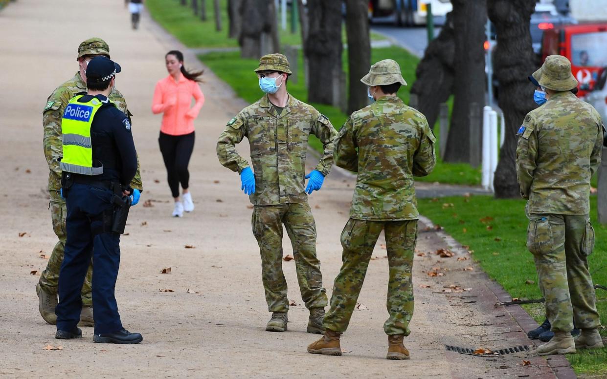 Police officers and soldiers patrol a popular running track in Melbourne to enforce new restrictive virus-control measures -  WILLIAM WEST/AFP