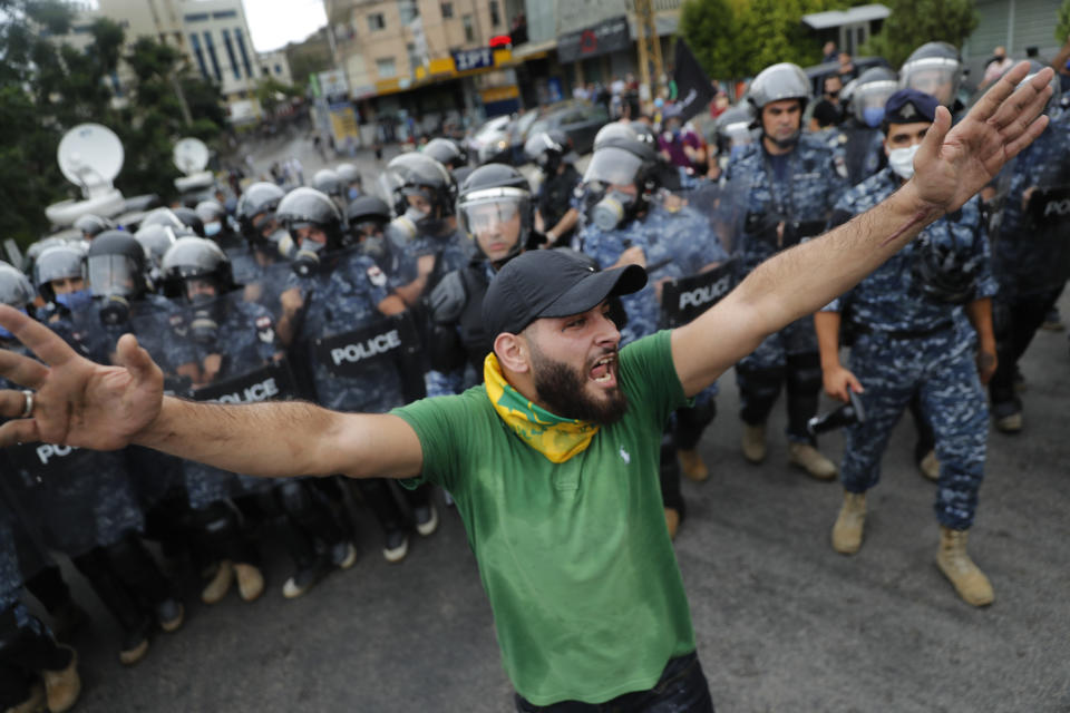 A Hezbollah supporter shouts slogans in front of riot police during a protest against the U.S. interference in Lebanon's affairs, near the U.S. embassy, in Aukar northeast of Beirut, Lebanon, Friday, July 10, 2020. (AP Photo/Hussein Malla)