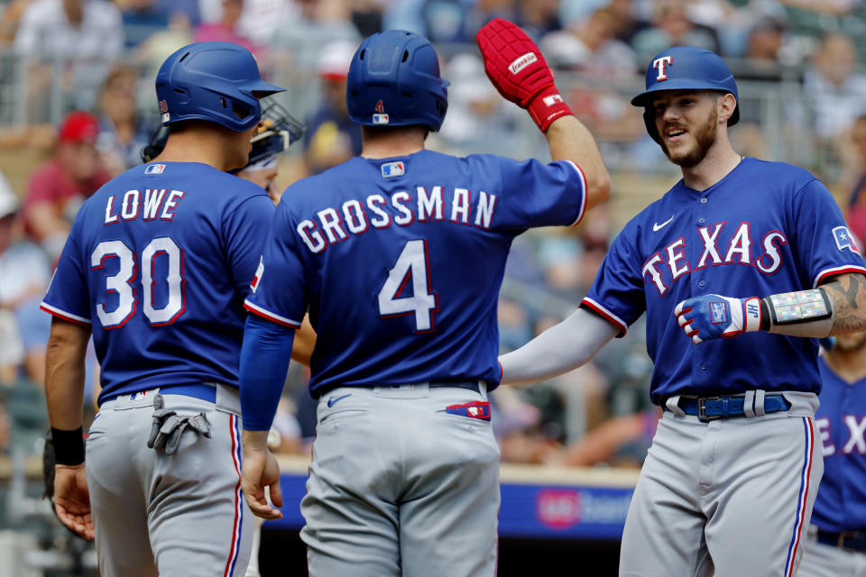 Texas Rangers' Jonah Heim, far right, celebrates his grand slam against the Minnesota Twins with Nate Lowe (30) and Robbie Grossman (4) in the fourth inning of a baseball game Sunday, Aug. 27, 2023, in Minneapolis. (AP Photo/Bruce Kluckhohn)