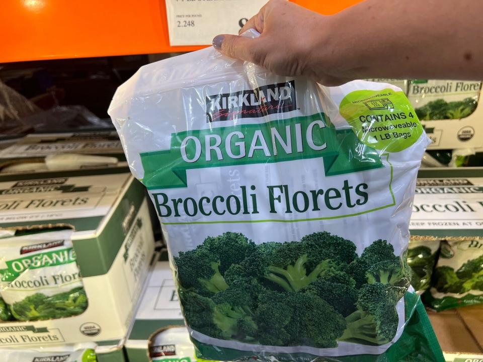 hand holding up a bulk bag of frozen broccoli at costco