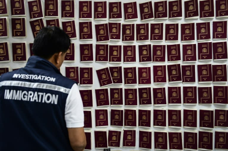 A Thai immigration detective looks at fake Spanish passports seized during the arrest of a master forger in Bangkok