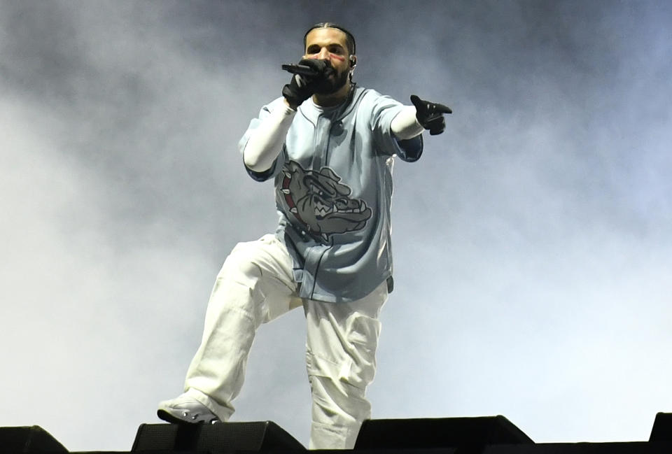 Drake performing in light blue bull dog jersey white pants and sneakers on stage at Dreamville Fest