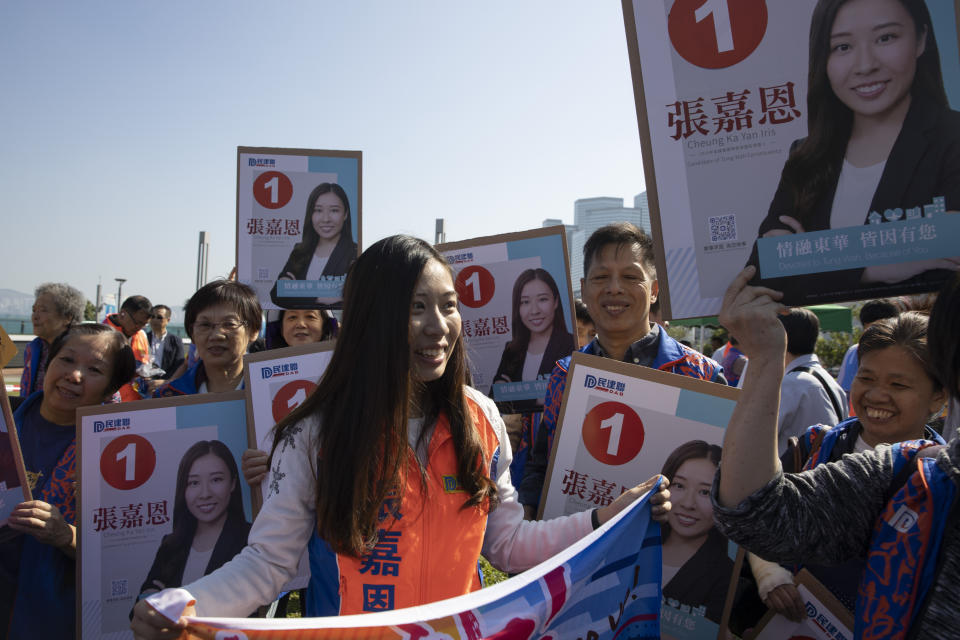 In this photo taken Thursday, Nov. 21, 2019. Pro-government candidate with the Democratic Alliance for the Betterment and Progress of Hong Kong, Cheung Ka Yan, a 26-year-old accountant, pose for photos with supporters during a campaign event in Hong Kong. Cheung says she jumped into the fray because many young people who support free elections for the city's leaders _ one of the protesters' key demands _ decry violence. b(AP Photo/Ng Han Guan)