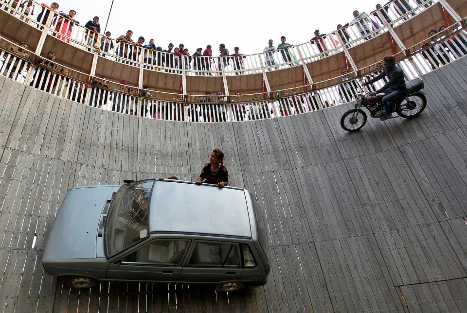 Stunt performers ride a motorcycle and a car on the walls of the “Well of Death” at the Magh Mela fair in Allahabad