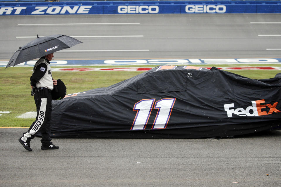 An official walks by the car of Denny Hamlin (11) car during a rain delay in a NASCAR Cup Series auto race at Talladega Superspeedway in Talladega, Ala., Sunday, Oct. 13, 2019. (AP Photo/Butch Dill)