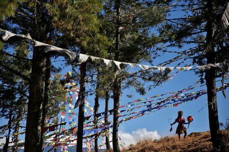 A masked dancer performs on the mountains above the capital city of Thimphu, Bhutan, December 12, 2017. REUTERS/Cathal McNaughton