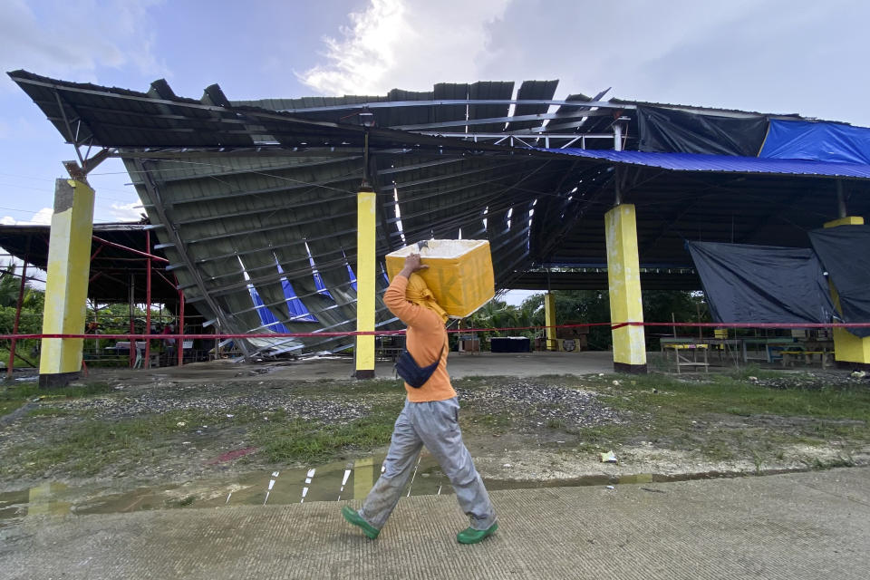 A fish vendor passes by a partially collapsed multipurpose covered court in Tagbina town, Agusan del Sur, southern Philippines on Sunday Dec. 3, 2023. A powerful earthquake struck Saturday off the southern Philippine coast, prompting many villagers to flee their homes in panic around midnight after Philippine authorities issued a tsunami warning. (AP Photo/Ivy Marie Mangadlao)