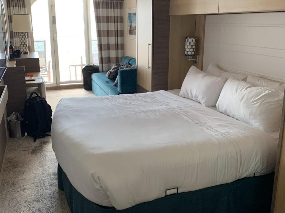 cruise ship room with large bed, small couch and balcony