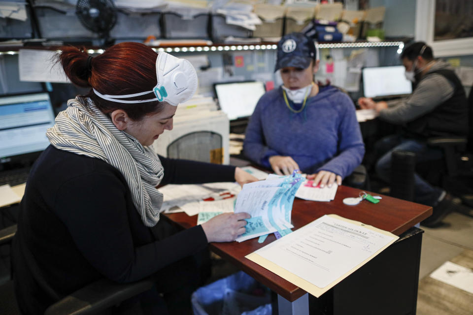 Employee Elysia Smith works through a stack of papers each denoting a body requiring retrieval from a hospital at Daniel J. Schaefer Funeral Home, Thursday, April 2, 2020, in the Brooklyn borough of New York. The new coronavirus causes mild or moderate symptoms for most people, but for some, especially older adults and people with existing health problems, it can cause more severe illness or death. (AP Photo/John Minchillo)