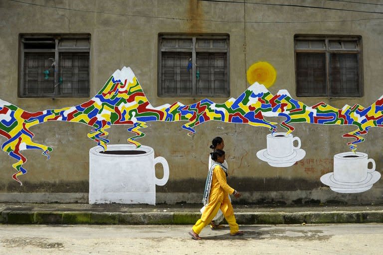 Nepalese walk past a mural in Kathmandu on August 20, 2013. Nepal's capital has been given a facelift thanks to a team of artists who painted dozens of elaborate and metres-high murals on walls