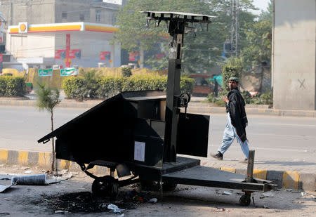 A passerby looks at a mobile CCTV unit destroyed during clashes with protesters near the Faizabad junction in Islamabad, Pakistan November 26, 2017. REUTERS/Caren Firouz