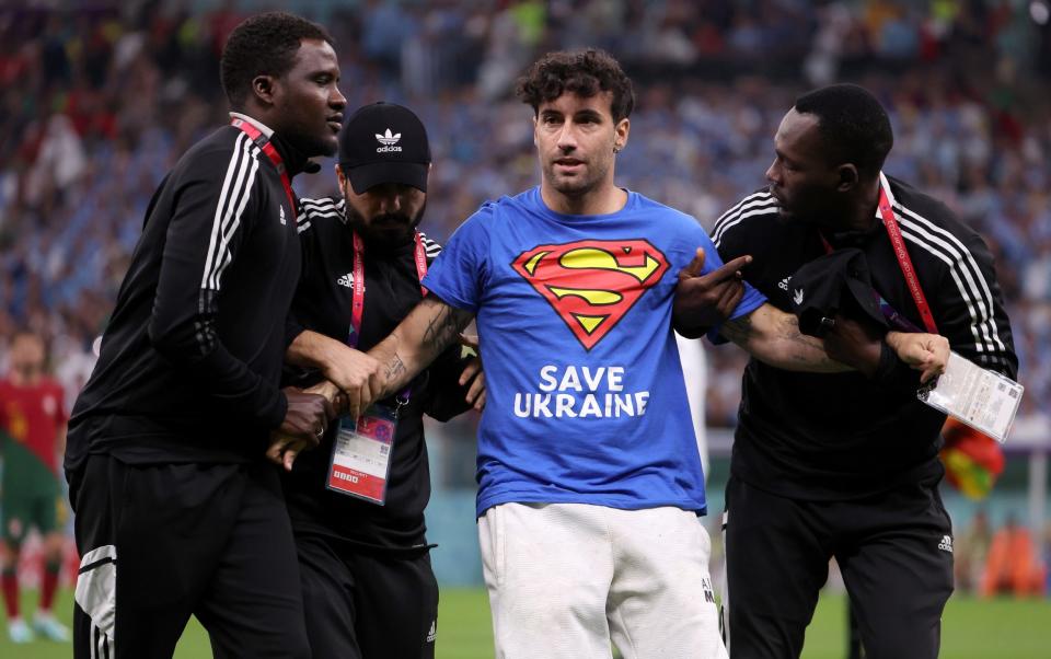 Mario Ferri is held by security after running onto the pitch - World Cup pitch invader with rainbow flag released by Qatar authorities - GETTY IMAGES/Jean Catuffe