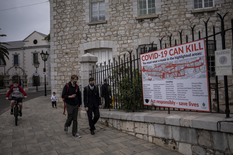 Schoolchildren walk by a COVID-19 informative banner in Gibraltar, Thursday, March 4, 2021. Gibraltar, a densely populated narrow peninsula at the mouth of the Mediterranean Sea, is emerging from a two-month lockdown with the help of a successful vaccination rollout. The British overseas territory is currently on track to complete by the end of March the vaccination of both its residents over age 16 and its vast imported workforce. But the recent easing of restrictions, in what authorities have christened “Operation Freedom,” leaves Gibraltar with the challenge of reopening to a globalized world with unequal access to coronavirus jabs. (AP Photo/Bernat Armangue)