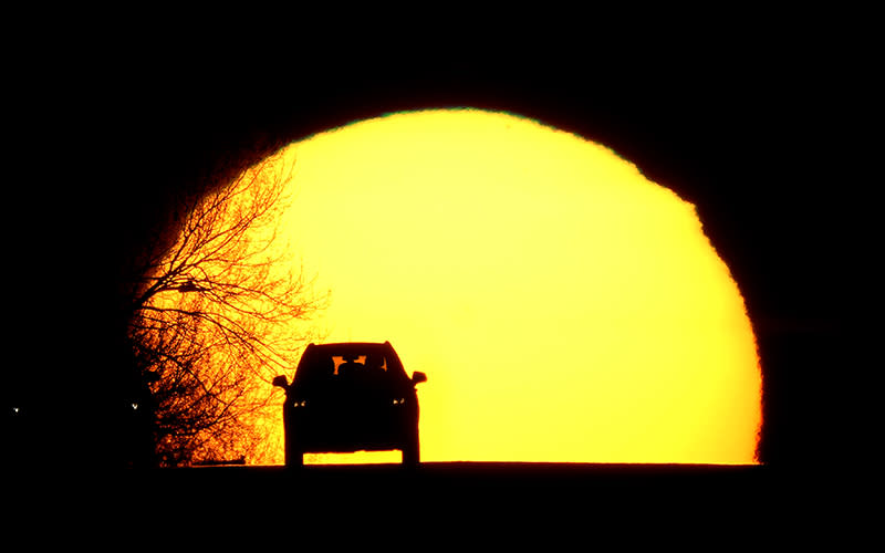 A motorist is silhouetted against the setting sun on the eve of the vernal equinox