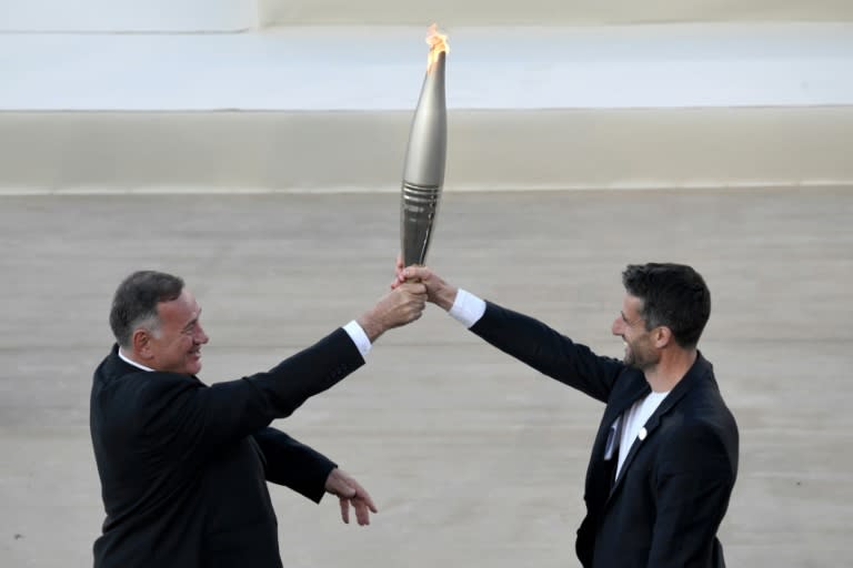 Le président du comité olympique hellénique Spyros Capralos (à gauche) remet la flamme olympique au président du Comité d'organisation des JO-2024 de Paris Tony Estanguet lors d'une cérémonie à Athènes le 26 avril 2024 (Angelos Tzortzinis)