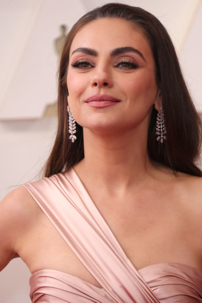 Close-up of Mila in a one-shoulder gown and long earrings