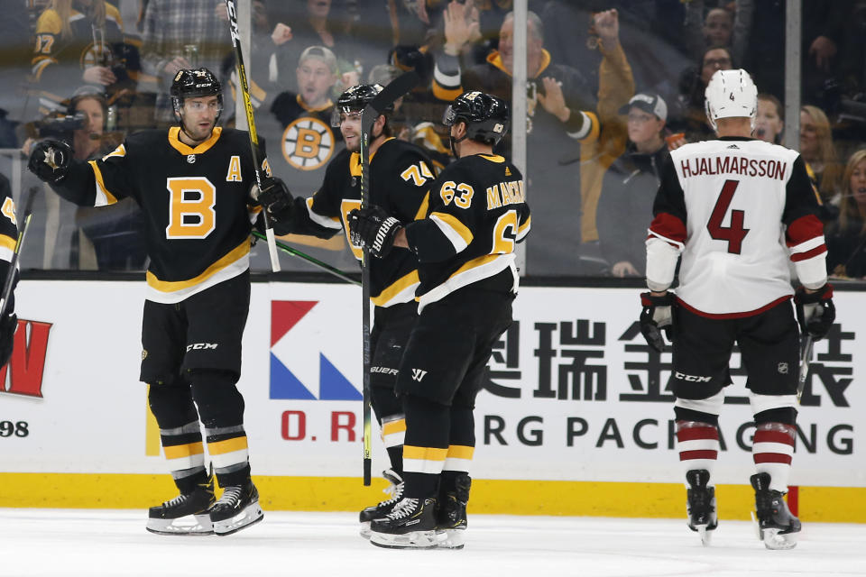 Boston Bruins' Patrice Bergeron, left, celebrates his goal with teammates Brad Marchand (63) and Jake DeBrusk as Arizona Coyotes' Niklas Hjalmarsson (4) skates away during the second period of an NHL hockey game Saturday, Feb. 8, 2020, in Boston. (AP Photo/Winslow Townson)