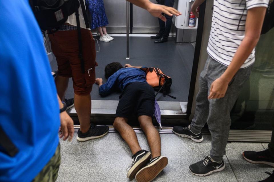 A man (C) falls down during a protest to prevent commuters from reaching work in business districts at Lai King MTR station in Hong Kong on August 5, 2019. | Philip Fong—AFP/Getty Images