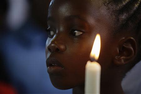 A girl holds a candle during a service for former South African President Nelson Mandela, in the Regina Mundi Church in Soweto December 8, 2013. REUTERS/Kevin Coombs