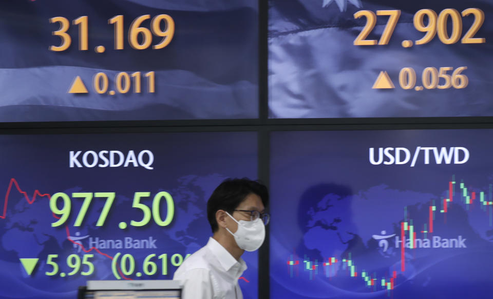 A currency trader walks near screens showing the Korean Securities Dealers Automated Quotations (KOSDAQ), left bottom, and the foreign exchange rates at a bank's foreign exchange dealing room in Seoul, South Korea, Monday, May 3, 2021. Shares were mostly lower in Asia in thin trading Monday, with many markets including those in Tokyo and Shanghai closed for holidays. (AP Photo/Lee Jin-man)