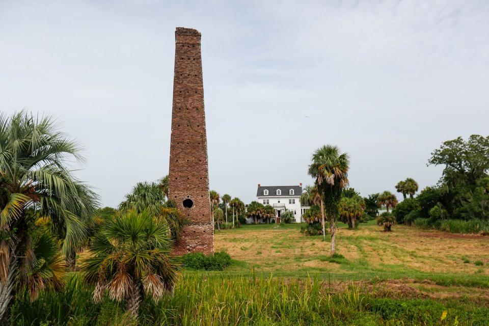 The chimney of a rice mill built on Butler Island Plantation in the middle of the 19th century stands in front of the Butler Island home built in the 1920s.