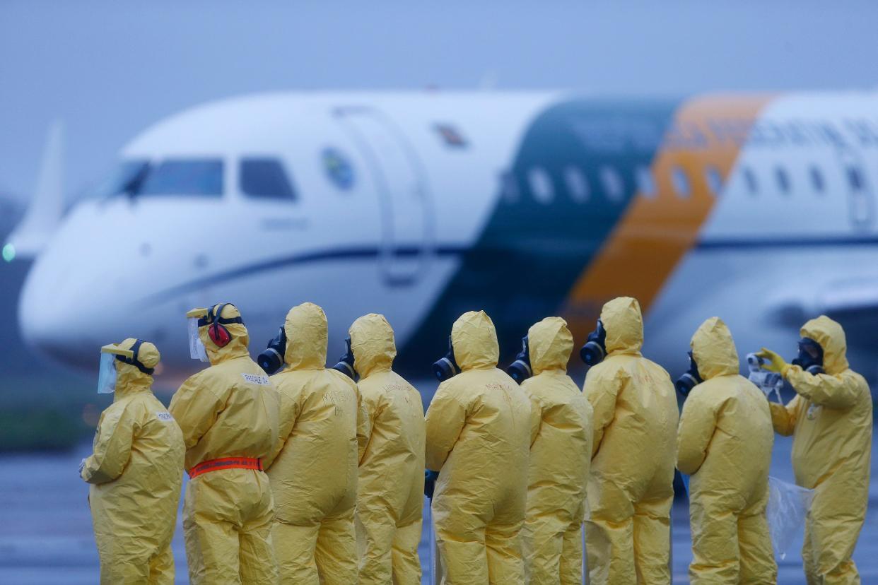 Soldiers wear protective suits during the arrival of Brazilians repatriated from Wuhan, China, the epicenter of the coronavirus, at the Annapolis Air Force Base, in Anapolis city, Goias state, Brazil, Sunday, Feb. 9, 2020. Dozens of Brazilians landed early Sunday morning at the airbase in the Brazilian state of Goias, where they will spend the next 18 days in quarantine. (AP Photo/Beto Barata)