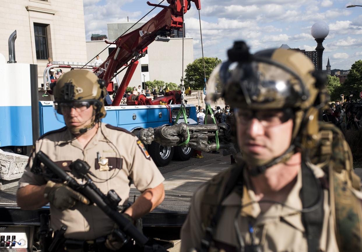 Members of the Minnesota State Patrol stand guard as a statue of Christopher Columbus, which was toppled to the ground by protesters, is loaded onto a truck on the grounds of the State Capitol on June 10, 2020 in St Paul, Minn.