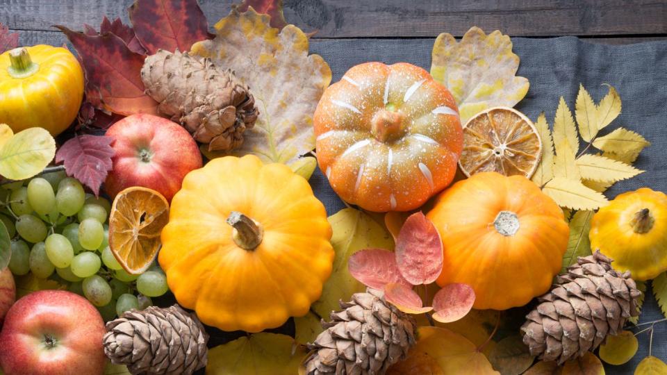 fall table place setting with orange dry leaves and pumpkins vertical format centerpieces thanksgiving day view from above