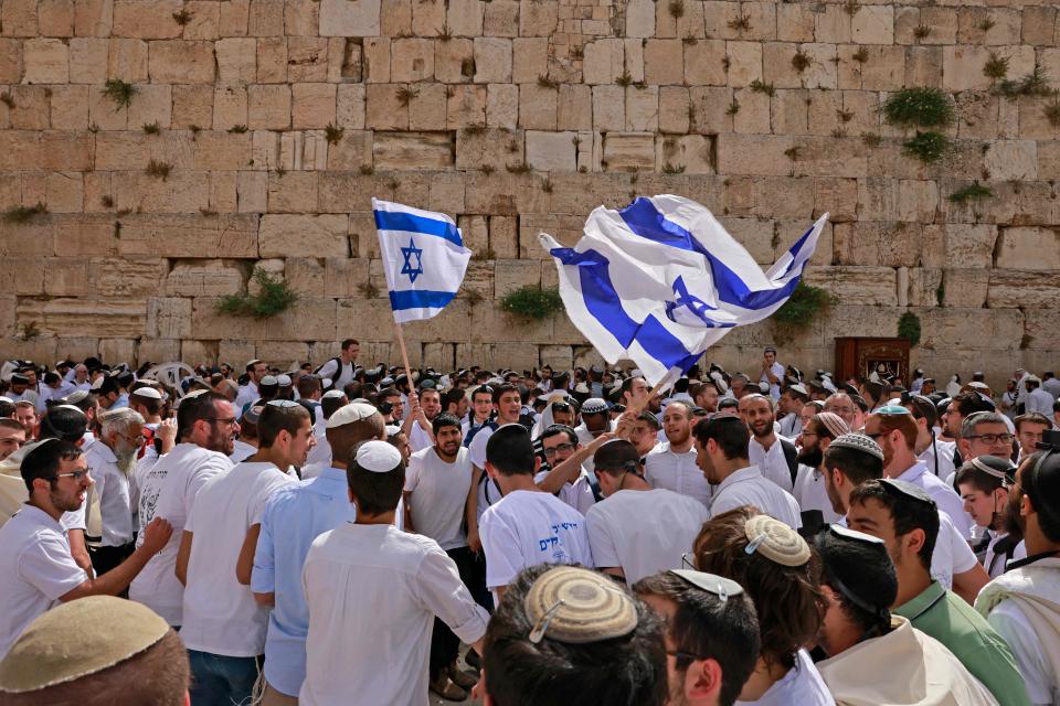 Jewish men wave Israeli flags as they gather at the Western Wall, the holiest site where Jews are allowed to pray, near al-Aqsa mosque in the Old City of Jerusalem on May 10, 2021, as Israel marks "Jerusalem Day."
