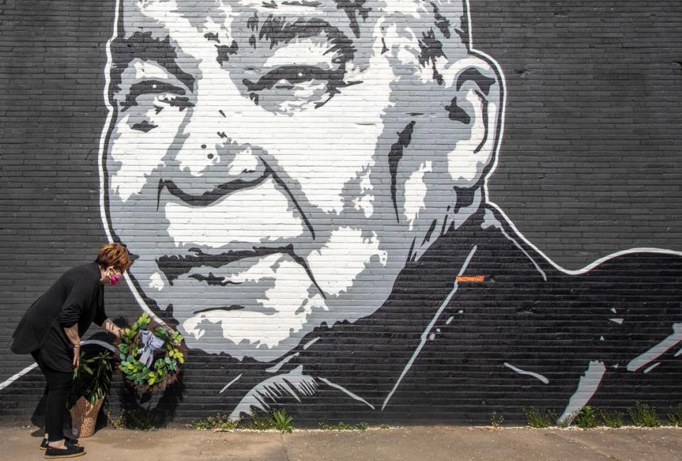 Maribeth Schmitt, of Lexington, places a wreath below a mural of singer John Prine, on the side of Apollo’s Pizza on Leestown Road in Lexington, on Wednesday, April 8, 2020. Prine, 73, died Tuesday at Nashville’s Vanderbilt University Medical Center following complications brought on by COVID-19. The mural was painted by Graham Allen of SquarePegs Studio and Design.