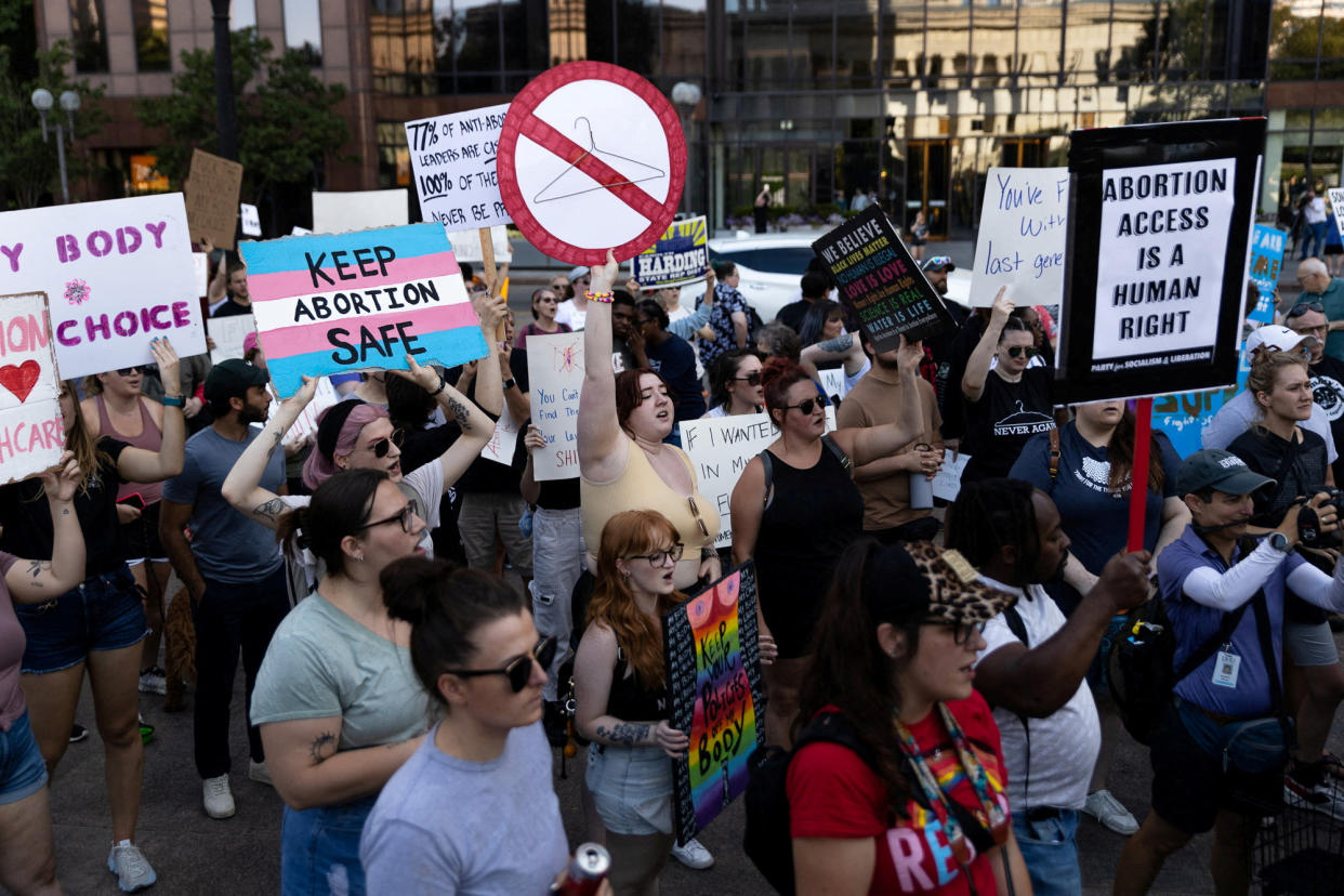 Protesters carry signs supporting abortion rights, such as ABORTION ACCESS IS A HUMAN RIGHT.