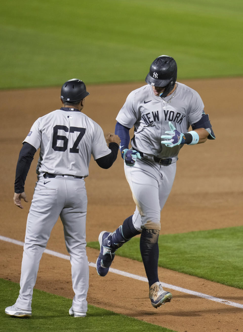 New York Yankees' Aaron Judge, right, celebrates with third base coach Luis Rojas (67) after hitting a solo home run during the seventh inning of a baseball game against the Oakland Athletics, Saturday, Sept. 21, 2024, in Oakland, Calif. (AP Photo/Godofredo A. Vásquez)