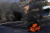 A military vehicle drives past tires set on fire by residents to protest against a police operation that resulted in multiple deaths, in the Complexo do Alemao favela in Rio de Janeiro, Brazil, Thursday, July 21, 2022. Police said in a statement it was targeting a criminal group in Rio largest complex of favelas, or low-income communities, that stole vehicles, cargo and banks, as well as invaded nearby neighborhoods. (AP Photo/Silvia Izquierdo)
