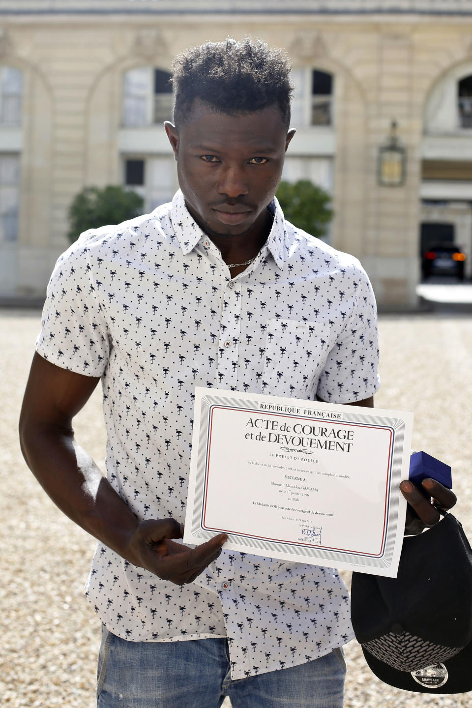 Mr Gassama displays a certificate of courage awarded to him by the Paris Police Prefect (Picture: AP)