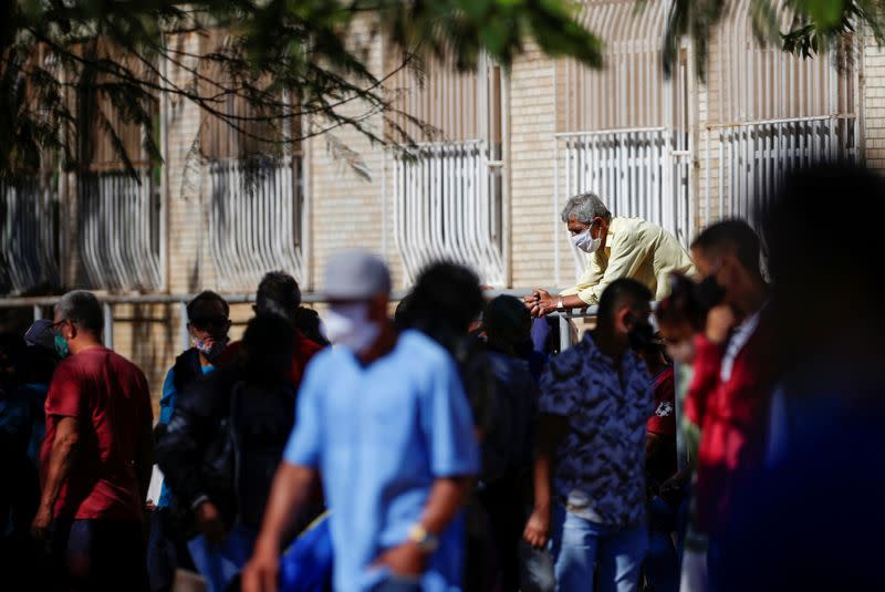 Un hombre con una mascarilla observa a una multitud en una calle en el vecindario de Ceilandia, en medio de la pandemia de COVID-19, en Brasilia