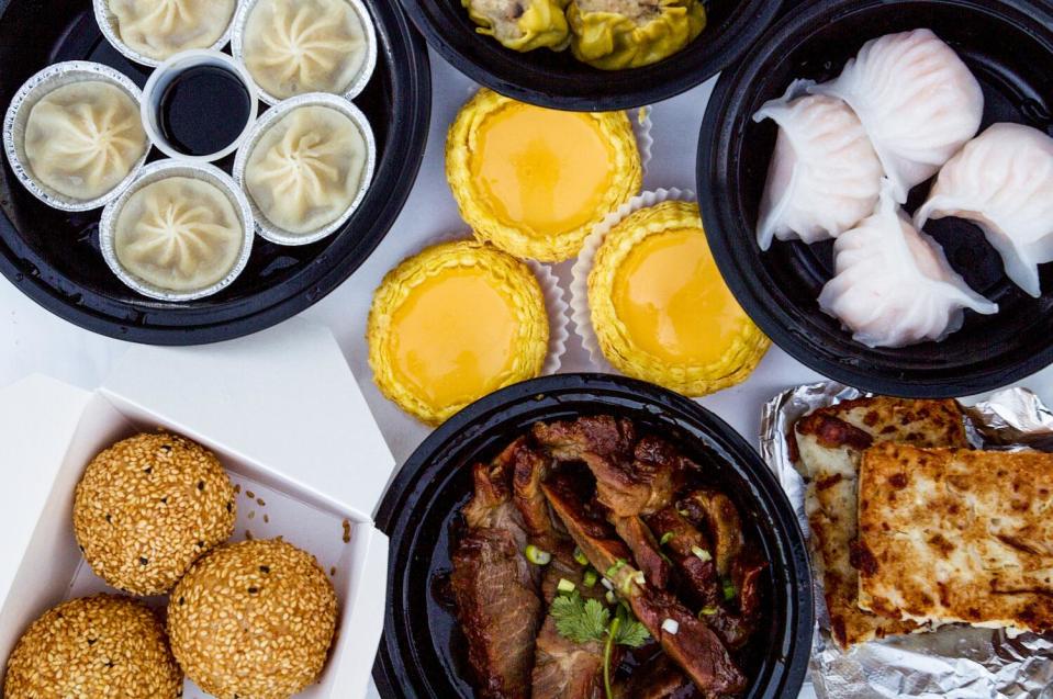 An overhead photo of egg tarts, har gao, xiao long bao, turnip cake, sesame balls and braised pork.