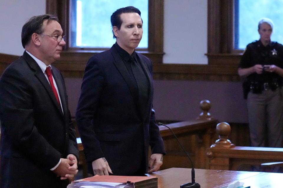 Musikalartisten Marilyn Manson, riktiga namnet Brian Hugh Warner (i mitten), står tillsammans med sin advokat Kent Barker under ett framträdande i Belknap Superior Court måndagen den 18 september 2023 i Laconia, NH Manson, som har åtalats för två fall av enkla fall. Han anklagades för misshandel för att ha närmat sig en videofotograf och påstås ha spottat och blåst hennes näsa vid hans konsert 2019 i New Hampshire.  (AP Photo/Charles Krupa)