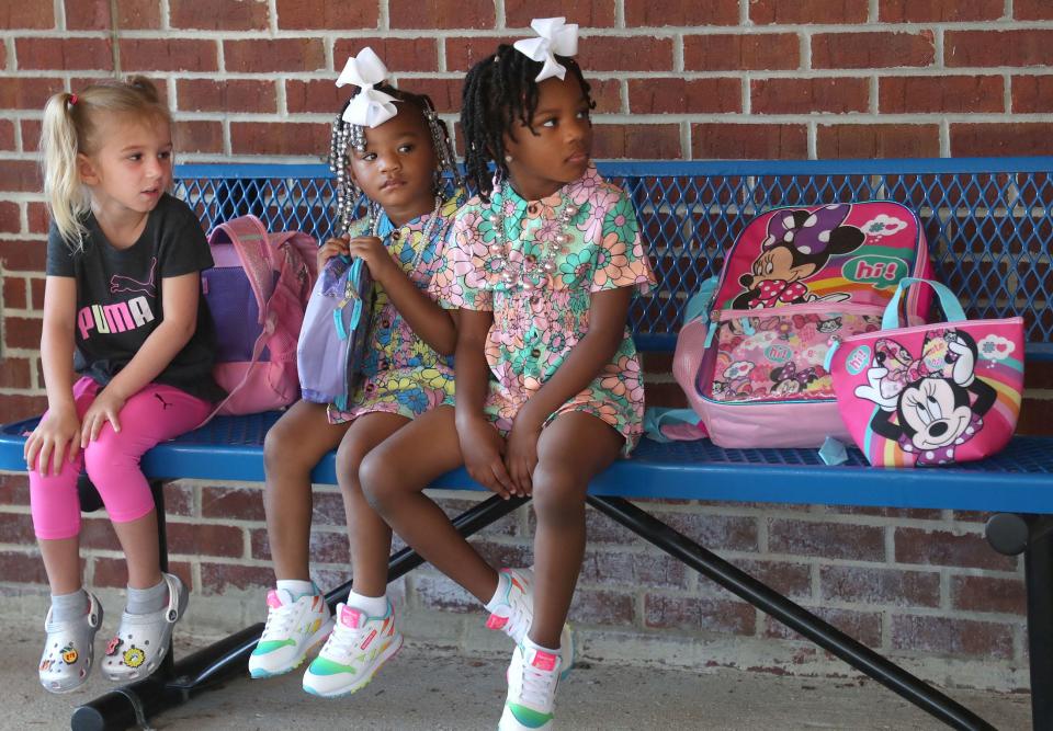 Student Tynleigh Hart waits with sisters Alaysha and Caliah Weary on Monday outside Palm Terrace Elementary School in Daytona Beach as students head back to classes for the 2022-2023 school year..