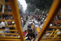 Muslim protesters are seen through a police barricade as they pray on a road near the historic Red Fort in New Delhi, India, Friday, Dec. 20, 2019. Police banned public gatherings in parts of the Indian capital and other cities for a third day Friday and cut internet services to try to stop growing protests against a new citizenship law that have so far left more than 10 people dead and more than 4,000 others detained. (AP Photo/Altaf Qadri)