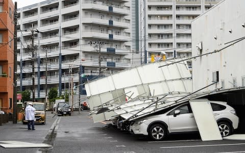 A temporary fence lies fallen on parked vehicles in Kawasaki, Kanagawa Prefecture - Credit: Bloomberg