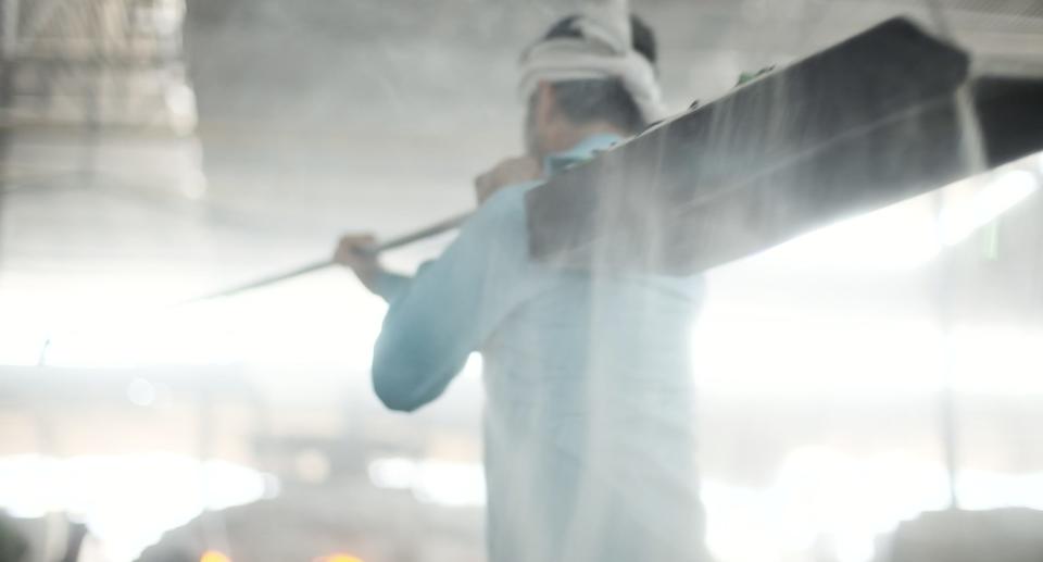 A man loads a shovel full of sand over his shoulder