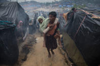 <p>A Rohingya man carries his handicapped mother to her tent October 7, Thainkhali camp, Cox’s Bazar, Bangladesh. (Photograph by Paula Bronstein/Getty Images) </p>