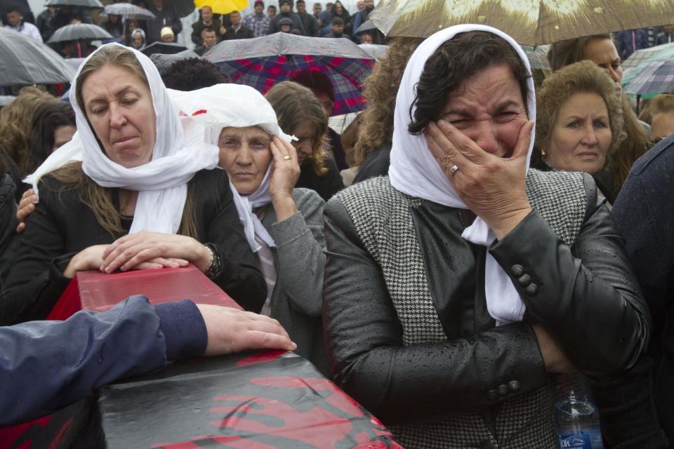 Ethnic Albanian woman weep next to a coffin draped with the Albanian flag containing the remains of her relative killed during the 1998-99 Kosovo war in the town of Mala Krusa during the funeral ceremony of 19 ethnic Albanians on Wednesday, March 26, 2014. The victims were killed in two separate rampages by Serbs forces in town of Suva Reka and Mala Krusa just days after NATO began a bombing campaign to end an onslaught by Serbia on separatist ethnic Albanians. (AP Photo/Visar Kryeziu)