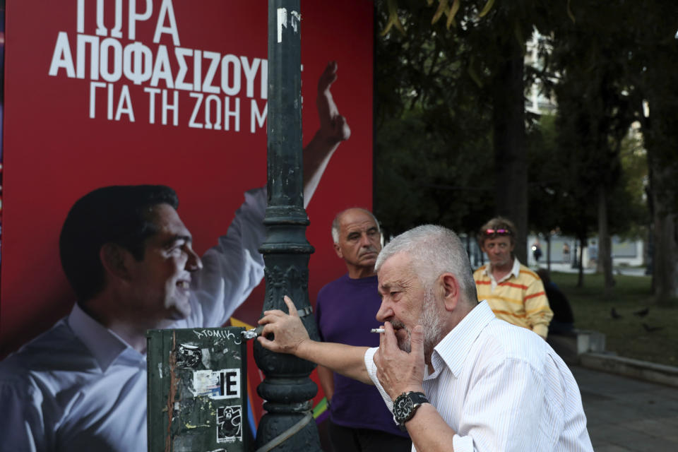 A supporter of left-wing Prime Minsiter Alexis Tsipras smokes a cigarette at the main election party kiosk during the parliamentary election in Athens, on Sunday, July 7, 2019. Official projections in Greece's parliamentary election showed the conservative opposition New Democracy party winning 39.8 percent of the vote compared to governing Syriza's 31.6 percent. (AP Photo/Yorgos Karahalis)